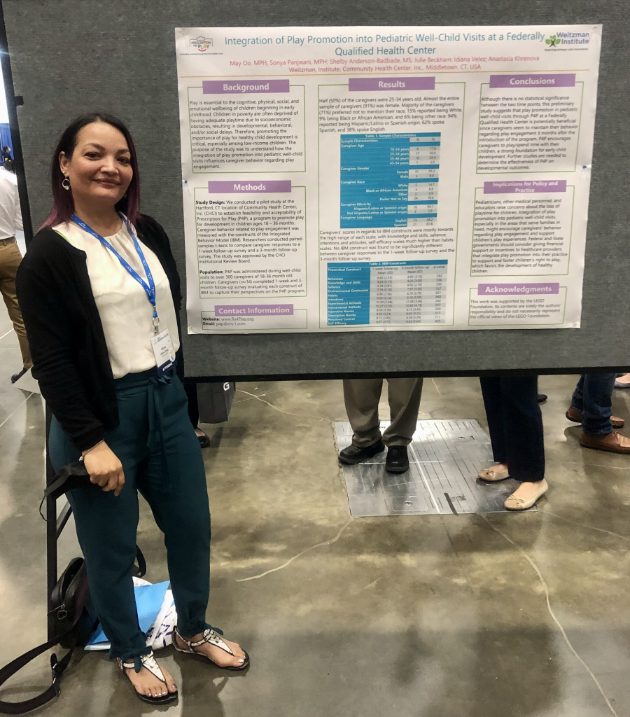 Idiana Velez poses beside a poster presentation at AcademyHealth conference.
